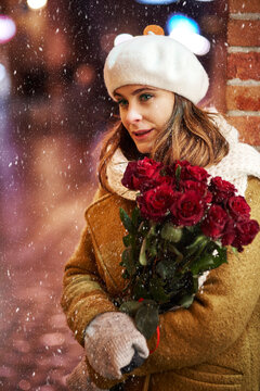 Portrait of young woman with bunch of red roses in winter