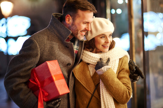 Happy couple looking in shop window at Christmas time