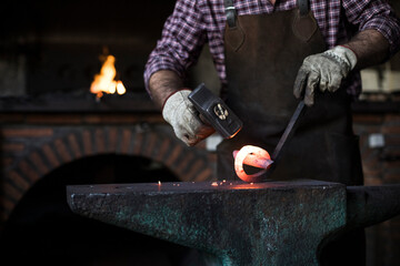 Close-up of blacksmith working with hammer at anvil in his workshop