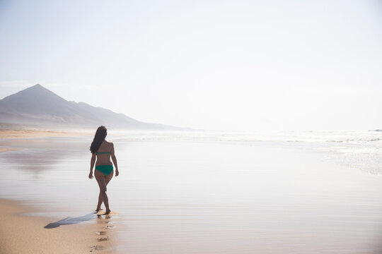 Back view of woman strolling on the beach at low tide, Fuerteventura, Spain