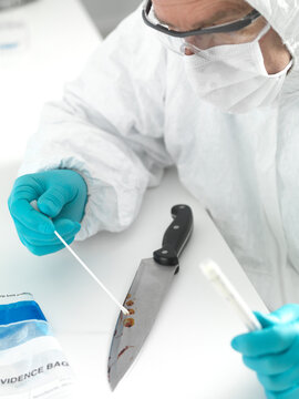 Forensic scientist taking DNA evidence from a blood smeared knife