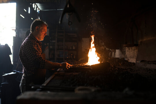 Blacksmith working at forge in his workshop