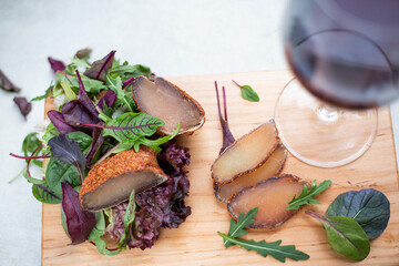 A piece of beef basturma and a glass of wine on a wooden table