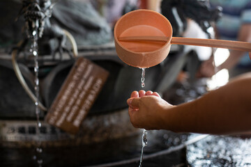 Young woman washing her hands before entering a temple in Tokyo, Japan