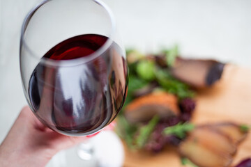Background blurred salad vegetables and balyk with a glass of wine