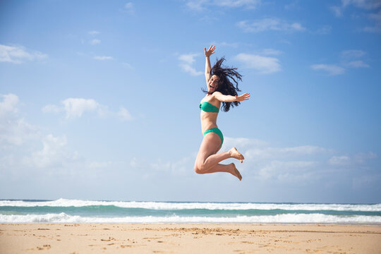 Laughing woman jumping in the air on the beach, Fuerteventura, Spain