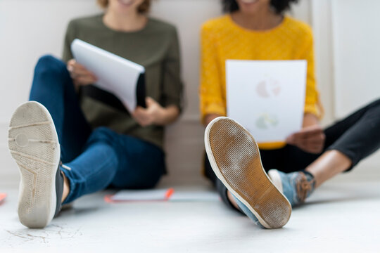 Colleagues in coworking space discussing business solutions, sitting on floor