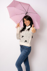 Portrait of a smiling beautiful woman holding umbrella with thumb up isolated over white background