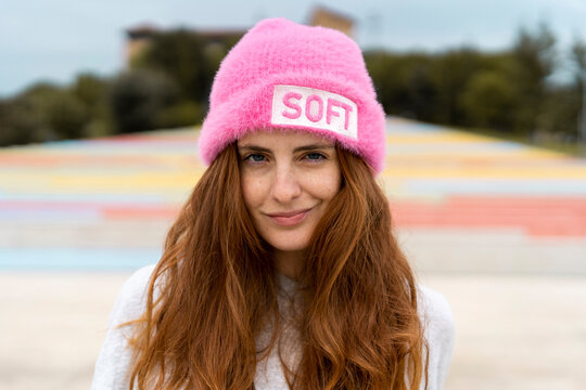 Portrait of redheaded woman wearing pink cap with the word 'soft'