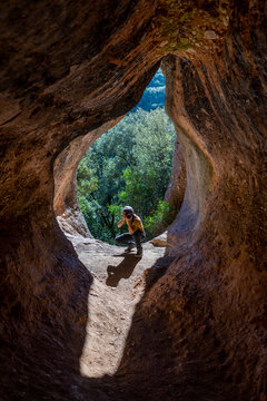 Young man taking pictures in cave entrance, Cova Simanya,Barcelona, Spain