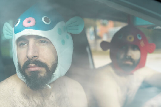 Portrait of gay couple in a car wearing animal hats