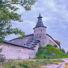 Fototapeta premium fragment of an old fortress wall with a corner watchtower in the ancient Russian city of Pskov