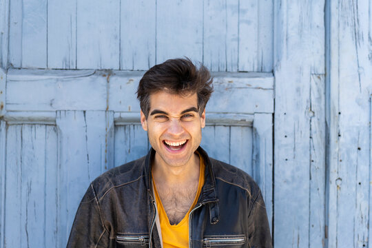 Portrait of laughing man in front of lightblue wooden door