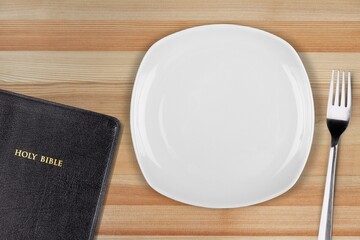 Fasting and prayer. Christian biblical concept, empty plate with Holy Bible.
