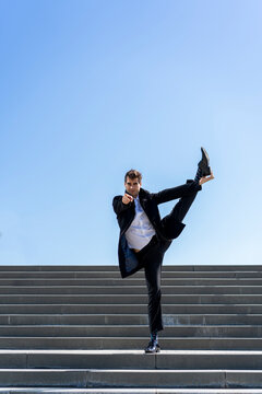 Businessman standing on on leg on stairs pointing his finger