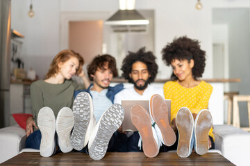 Friends sitting on couch, watching laptop