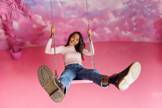 Portrait of happy young woman on a swing at an indoor theme park