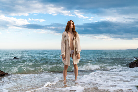 Redheaded young woman standing in front of the sea