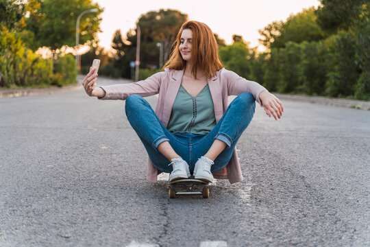 Young woman on skateboard and taking a selfie
