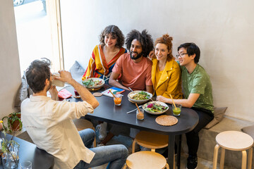 Group of friends having lunch in a restaurant taking a picture