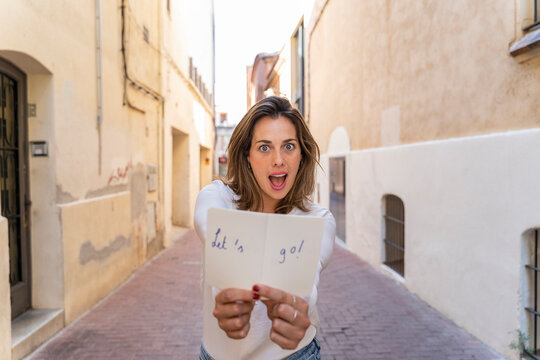 Young woman with notebook 'Let's go!' in an alley