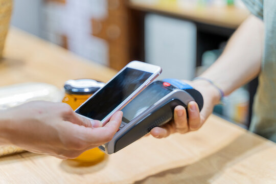 Customer paying cashless with smartphone in a shop