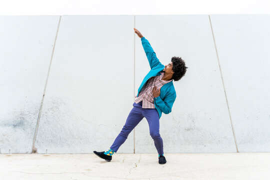 Young hipster man dancing, white wall in the background
