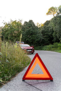 Warning triangle in front of a broken car on a country road