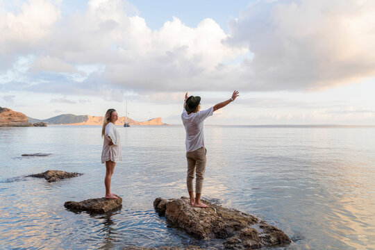 Young couple standing on rocks in front of the sea, Ibiza, Balearic Islands, Spain