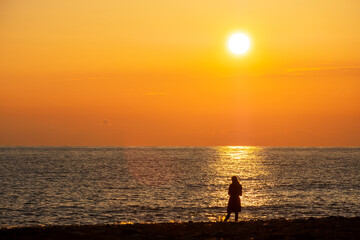 orange sunset on the sea with a bright sun. the silhouette of a man against the background of a bright sunny path