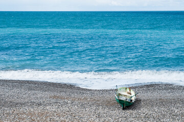 an old plastic fishing boat is near the water on the seashore