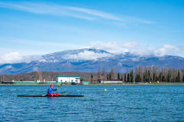Adler, Russia - March 27, 2021 a man rower floats on a kayak rowing oars. background mountain landscape. rest at nature