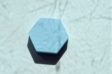 Empty hexagon pastel light blue platform podium on white background with natural light and shadows....