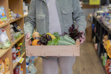 Close-up of senior man carrying crate with vegetables in a small food store