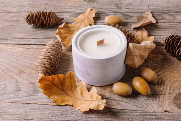 Fototapeta na wymiar Natural handmade soy candle on wooden background. Scented candle for interior. Cozy autumn composition