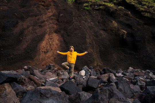 Man standing amidst volcanic rocks in yoga pose, Sao Miguel Island, Azores, Portugal