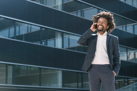 Smiling Businessman Talking On Cell Phone Outside Office