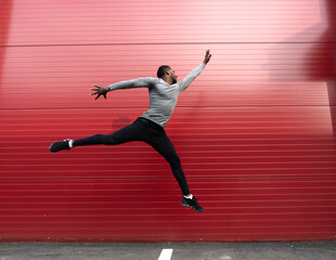 Athlete jumping in front of a red wall