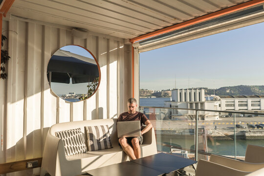 Man using laptop on a sunny terrace, Lisbon, Portugal