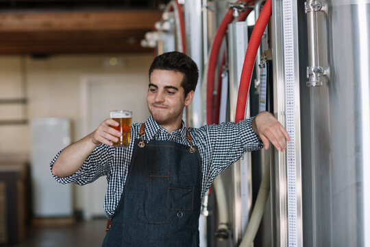 Portrait of confident young man holding beer glass at a brewery - Powered by Adobe