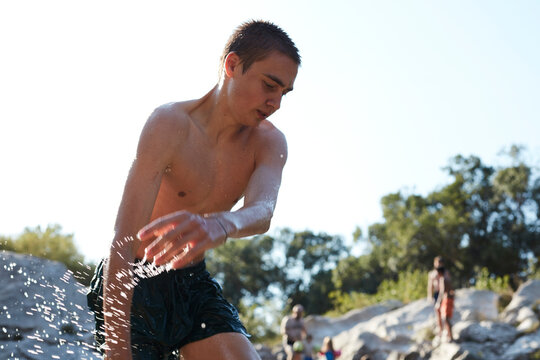 France, portrait of teenage boy bathing in lake splashing with water