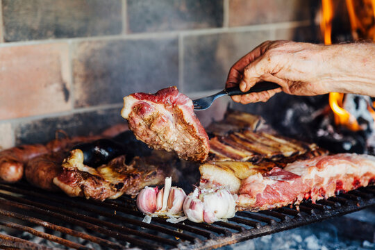 Argentinian meat roasting on the grill. Man making a traditional barbecue called Asado in Argentina.