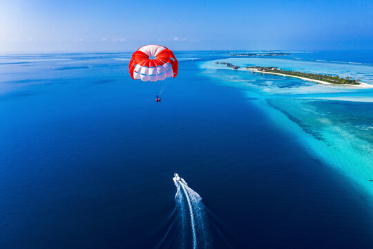 Maledives, South Male Atoll, paraglider flying along an atoll, aerial view