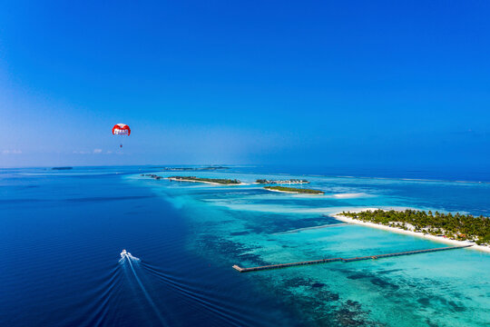 Maledives, South Male Atoll, paraglider flying along an atoll, aerial view