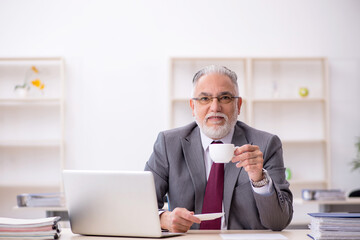 Old male employee drinking coffee during break