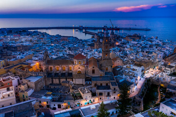 Italy, Apulia, Monopoli, Aerial view of sea and old town at sunset