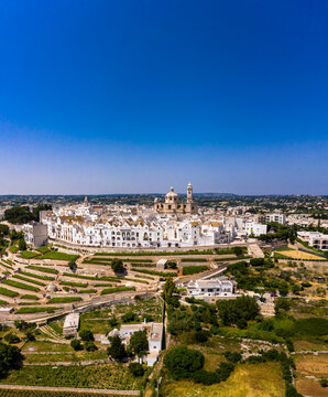 Italy, Locorotondo, Aerial view of clear blue sky over vineyards in front of white town buildings