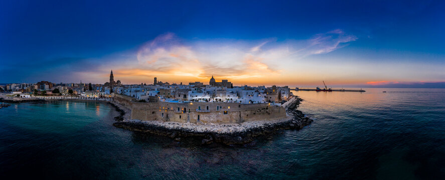 Italy, Apulia, Monopoli, Aerial view of sea and old town at sunset