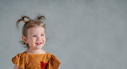 Close-up portrait of smiling child on gray background. Happy childhood