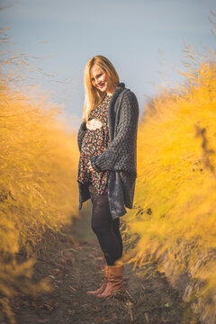 Smiling pregnant woman standing in asparagus field in autumn